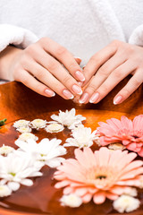 Obraz na płótnie Canvas cropped view of woman making spa procedure with flowers, nail care concept