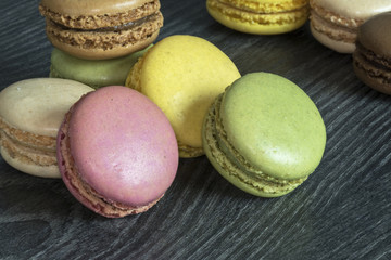 Macarons de couleurs différentes en tas sur fond noir