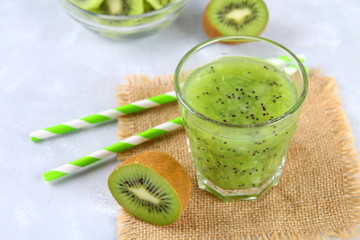Sliced kiwi and smoothie slices in a glass on a gray table. Healthy food.