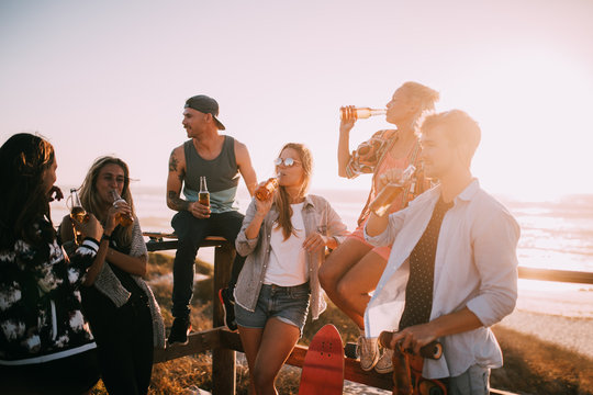 Group of young adult friends drinking beer at the beach party