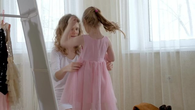 Mother helps her daughter to dress in a costume