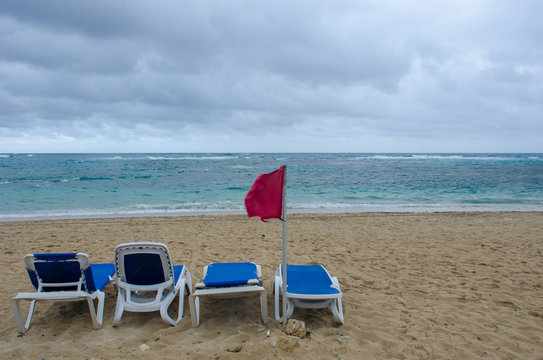 Empty sundeds on dangerous resort beach with red flag