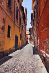 Fototapeta na wymiar Narrow Italian street with colorful houses without people on a sunny day Rome, Italy