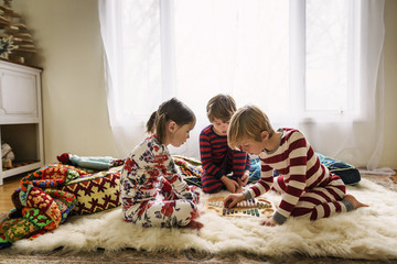 Three children sitting on the floor playing a board game