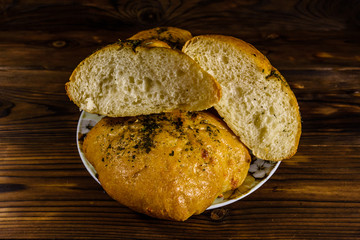Plate with italian bun ciabatta on wooden table