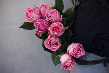 The big bouquet of beautiful pink roses in woman hands on gray background