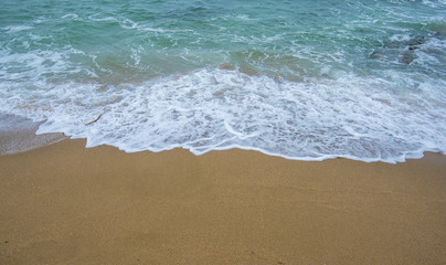 Fototapeta na wymiar Turquoise wave wrecked on the yellow sand