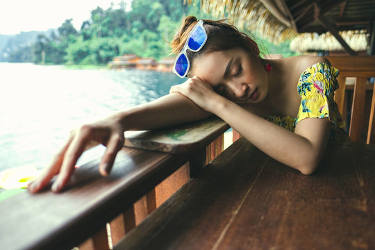 lonely Girl sleep on table wood in holiday with blur lake view background
