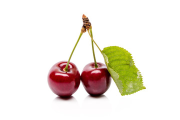 Two Cherry berries with green leaf isolated on a white background