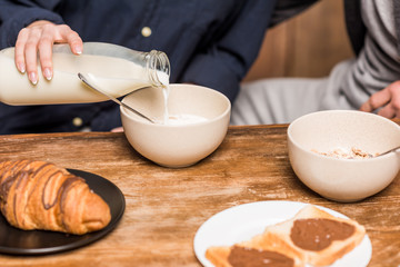 cropped image of girlfriend pouring milk in plate