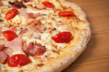 Tasty Italian pizza with ham, cherry tomatoes and parmesan on wooden table. Top view