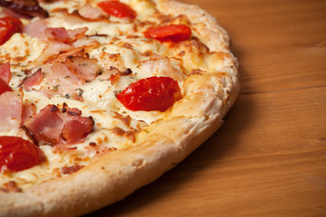 Delicious Italian pizza with ham, cherry tomatoes and parmesan on wooden table. Top view