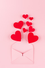 Opened paper envelope with red hearts as love message on soft pink color background. Valentine day concept for design.