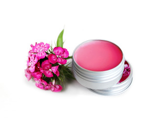 pink lip balm in the container with a pink flower near it