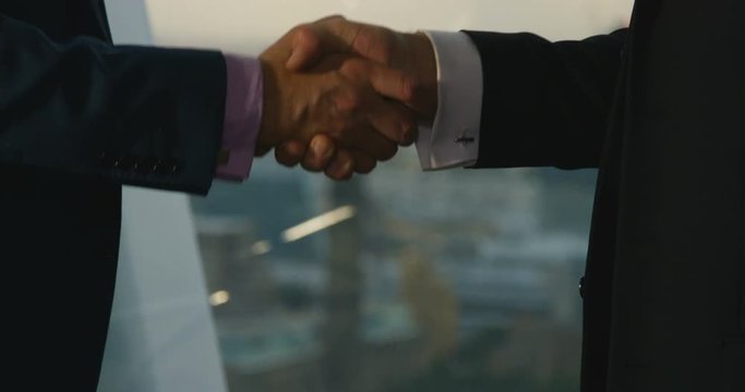 4K Close up on hands of business partners shaking hands on a deal. City office boardroom view of London seen from window.