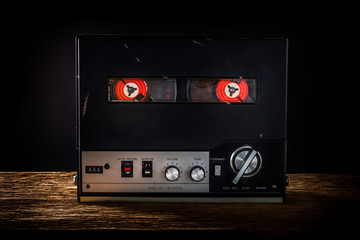 Tape recorder on wooden table with black background