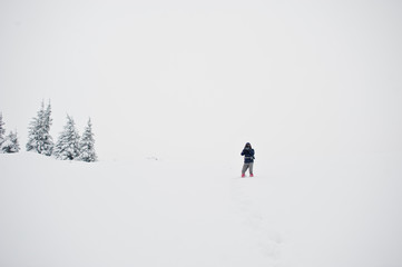 Man tourist photographer with backpack, at mountain with pine trees covered by snow. Beautiful winter landscapes. Frost nature.