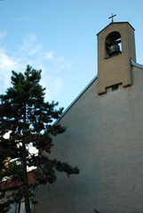 Fototapeta na wymiar Glockenturm mit Kreuz Ein Glockenturm mit Glocke und Kreuz ragt in den blauen Himmel. 