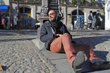 Man portrait; man is sitting on the street on a sunny day; people and street life concept.