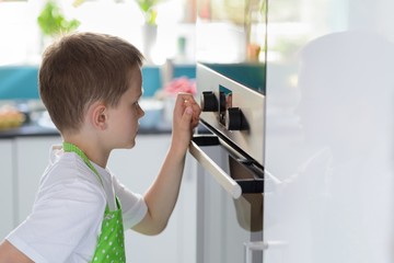 Fototapeta na wymiar Child boy regulating temperature of the oven.