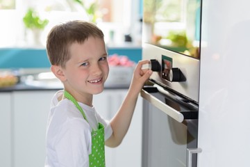 Child boy regulating temperature of the oven.