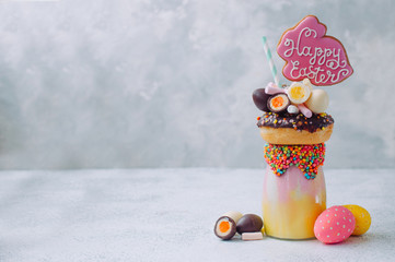 Easter freak shake decorated with Easter bunny gingerbread on grey background