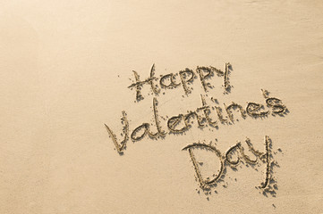 Happy Valentine's Day message handwritten on smooth sand beach