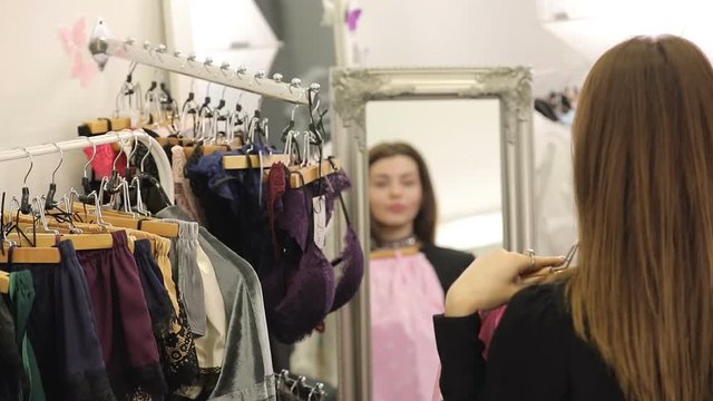 Young woman is shopping, choosing pajamas in boutique