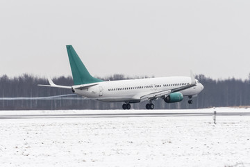 Airplane take off from the snow-covered runway airport in bad weather during a snow storm, a strong wind in the winter.