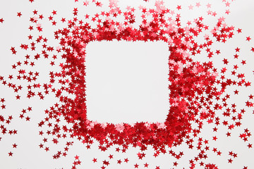 Confetti. Frame made of colored red star confetti front of white background. Copy space