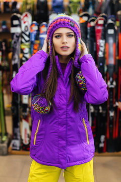 Girl in yellow and violet ski suit stands in the ski store