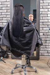 Naklejka premium Female young client with long wet hair sitting in armchair in front of the mirror