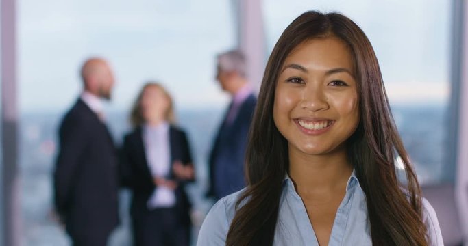 4K Portrait smiling businesswoman in city office with colleagues talking in background. Slow motion.