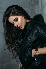 Naklejka premium Portrait of a sexy girl with naked legs and in leather jacket posing in dark studio
