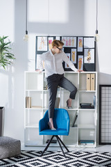 Fototapeta na wymiar stylish attractive fashion designer standing on chair at office