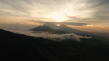 Beautiful sunset in the mountains on Jawa island, Indonesia. Aerial view of mountains landscape under sky with clouds, rainforest.