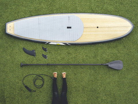 Paddle surf still life, paddle board, keels, row, leash and woman legs on wet suit