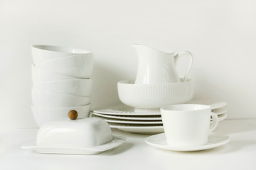 White tableware for serving. Crockery,dish, utensils and other different white stuff on white table-top. Kitchen still life as background. Copy space.