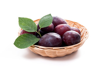 Yellow wooden basket with ripe plums isolated on a white background..