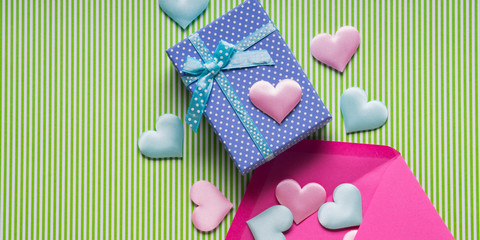 Blue gift box, hearts and envelope on pastel green. Flat lay Valentine's woman mother day concept