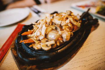 Close up view of female hand holding meat in chopsticks while eating Chinese food in the restaurant.