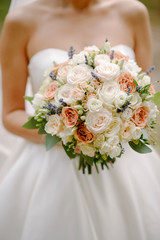 Bride's hands hold a beautiful wedding bouquet