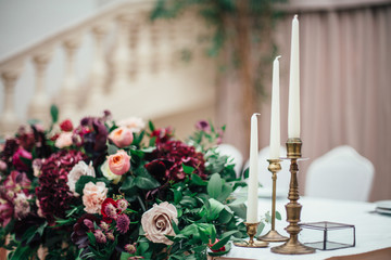 Rich bouquet of red, pink and white roses and greenery stands on the table in a luxury restaurant