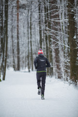 Photo from back of running athlete among trees in winter forest