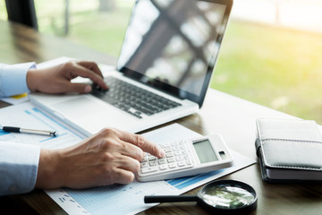 Fototapeta premium Business man working at office with laptop, tablet and graph data documents on his desk