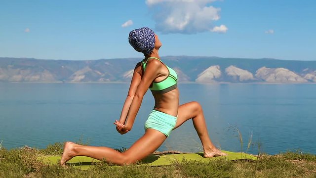 Slender woman practicing yoga near the giant blue lake baikal.