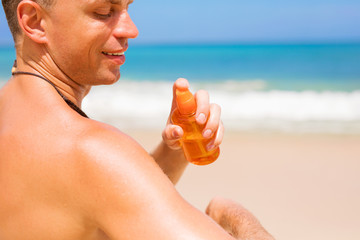 Man apply sunscreen on his body on the beach