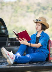 Woman wear hat and reading the book on pickup truck