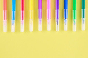 Colored pens on a yellow background