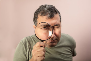 Fototapeta na wymiar Man looking through magnifying glass